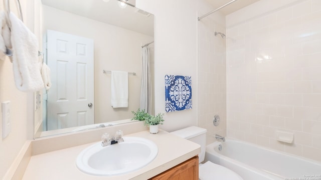 full bathroom featuring tiled shower / bath combo, vanity, and toilet