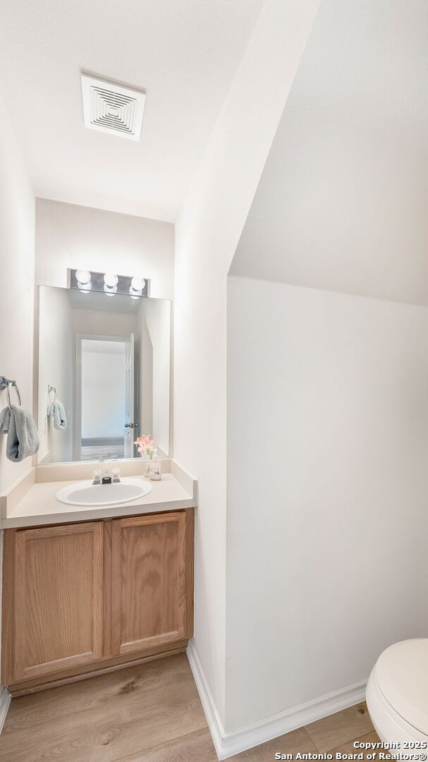 bathroom with hardwood / wood-style flooring, vanity, and toilet