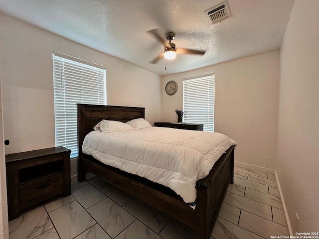 bedroom with ceiling fan and a textured ceiling