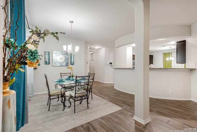 dining area with wood-type flooring and a chandelier