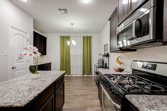 kitchen with appliances with stainless steel finishes, decorative backsplash, a center island, dark brown cabinets, and light hardwood / wood-style flooring