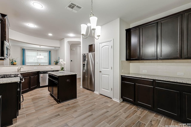 kitchen featuring pendant lighting, light stone countertops, stainless steel appliances, and a center island