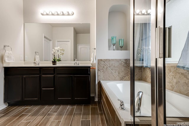 bathroom with vanity and tiled tub