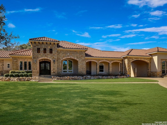 mediterranean / spanish home featuring a front yard and french doors