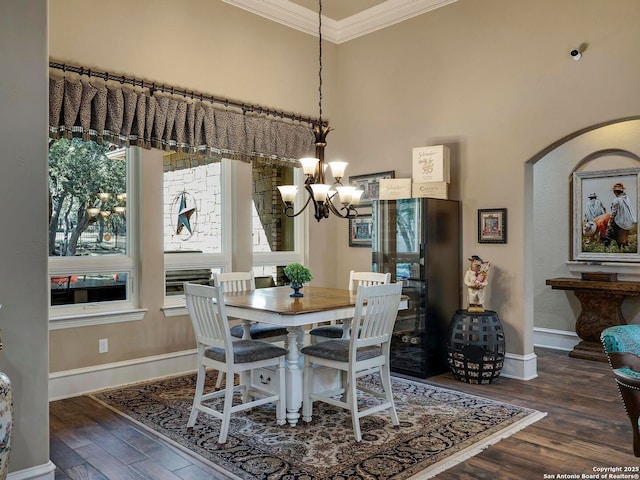 dining room featuring dark hardwood / wood-style flooring, crown molding, a high ceiling, and an inviting chandelier