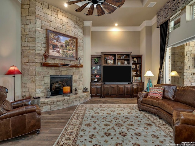 living room featuring ornamental molding, hardwood / wood-style floors, ceiling fan, and a fireplace