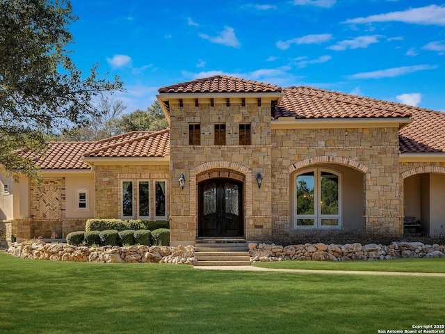 mediterranean / spanish-style house with a front yard and french doors