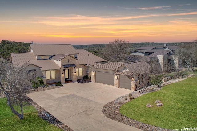 view of front of home with metal roof, a garage, concrete driveway, a front lawn, and a standing seam roof