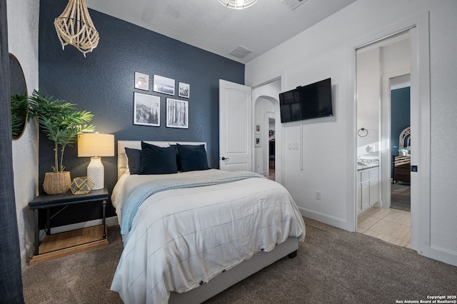 bedroom with ensuite bath and carpet