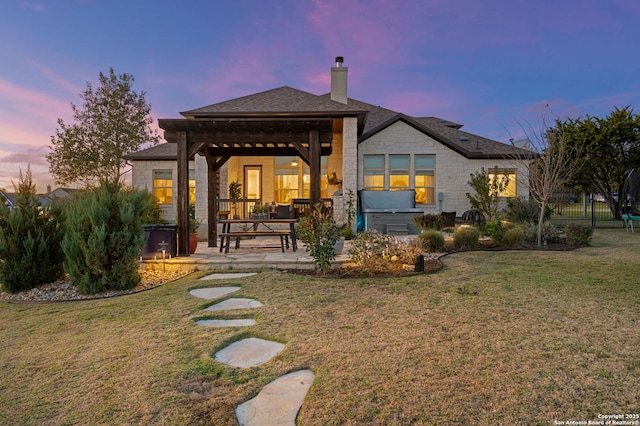 back house at dusk featuring a yard, a hot tub, and a patio