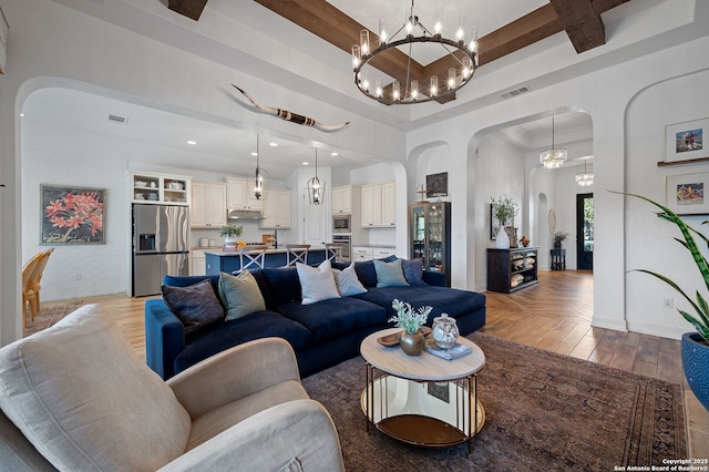 living room featuring a chandelier, a raised ceiling, beamed ceiling, a towering ceiling, and light parquet floors