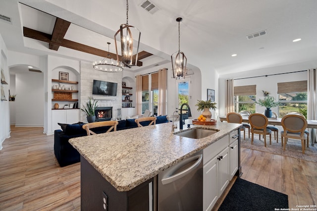 kitchen with stainless steel dishwasher, sink, a center island with sink, and white cabinets