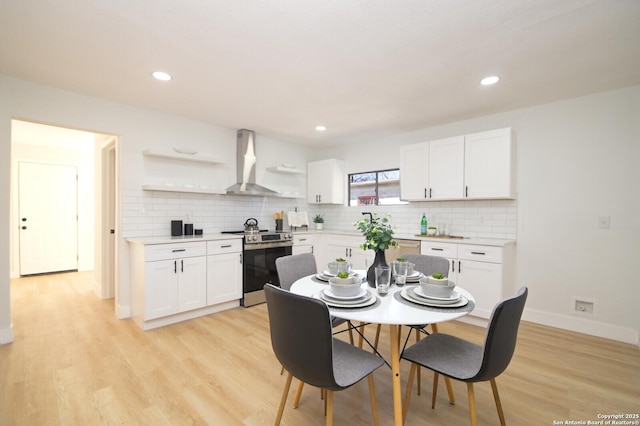 kitchen with electric stove, white cabinets, light hardwood / wood-style floors, and wall chimney range hood