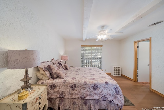 bedroom with beam ceiling, ceiling fan, and light hardwood / wood-style flooring