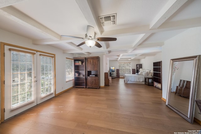 unfurnished living room featuring coffered ceiling, beam ceiling, light hardwood / wood-style flooring, and french doors