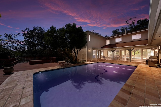 pool at dusk featuring a patio