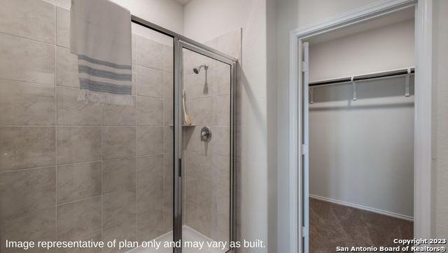 full bath featuring a shower stall and a spacious closet