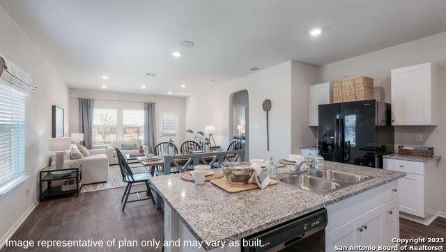 kitchen with arched walkways, a sink, black appliances, dark wood-style floors, and open floor plan