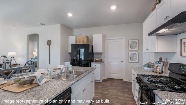 kitchen with a sink, under cabinet range hood, white cabinets, arched walkways, and black appliances