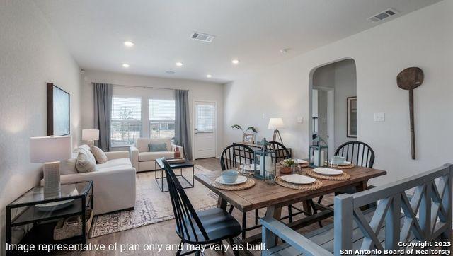 dining space with arched walkways, recessed lighting, wood finished floors, and visible vents