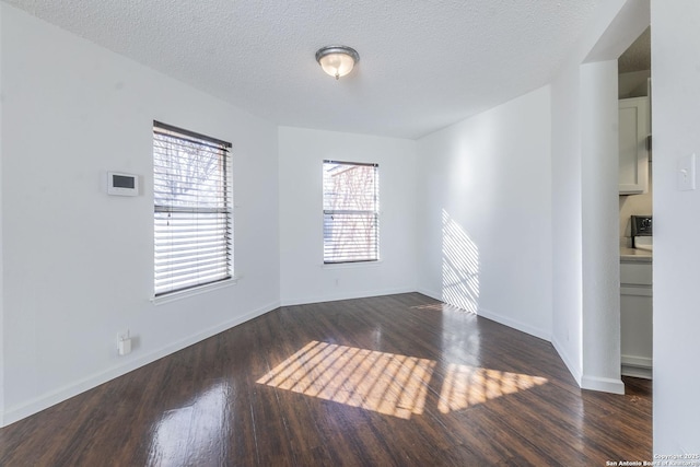 spare room featuring dark hardwood / wood-style flooring and a textured ceiling