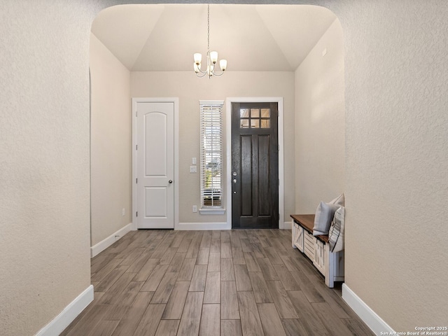 entryway featuring hardwood / wood-style flooring, lofted ceiling, and a notable chandelier