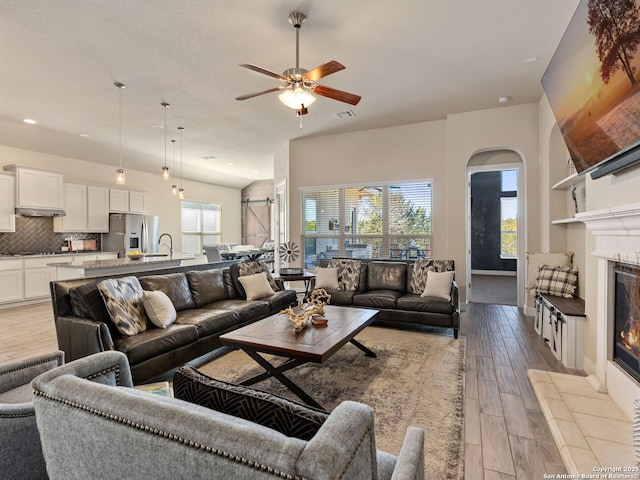 living room with sink, light hardwood / wood-style flooring, a tile fireplace, and a textured ceiling