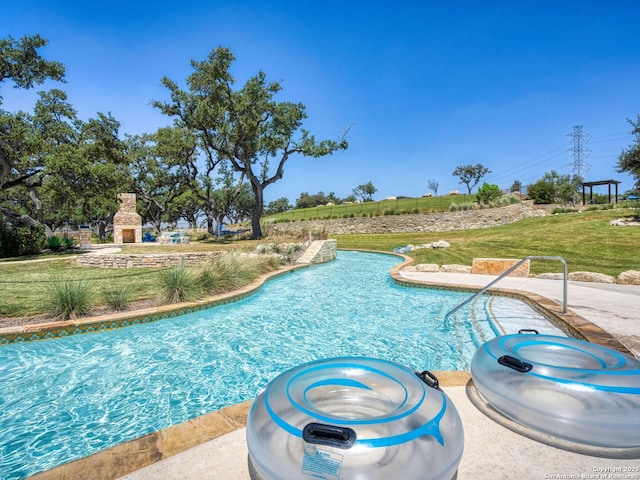 view of pool with a yard and a fireplace