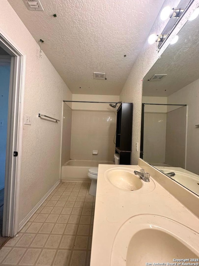 full bathroom featuring vanity, a textured ceiling, tiled shower / bath combo, and toilet