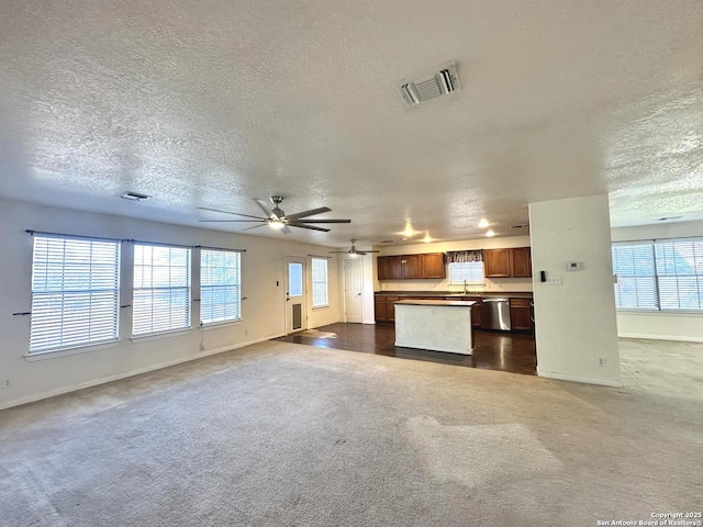 unfurnished living room with sink, dark carpet, a healthy amount of sunlight, and ceiling fan