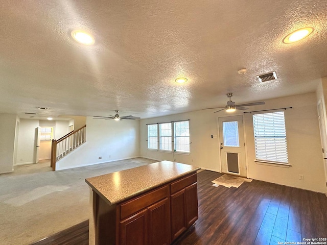 kitchen with dark hardwood / wood-style flooring, a textured ceiling, a center island, and ceiling fan