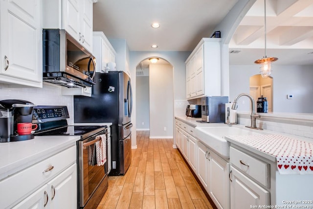 kitchen with sink, light wood-type flooring, pendant lighting, stainless steel appliances, and white cabinets