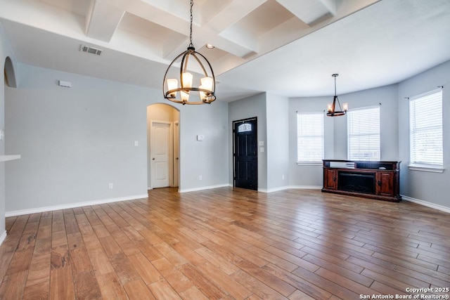 unfurnished living room with plenty of natural light, a chandelier, and hardwood / wood-style floors