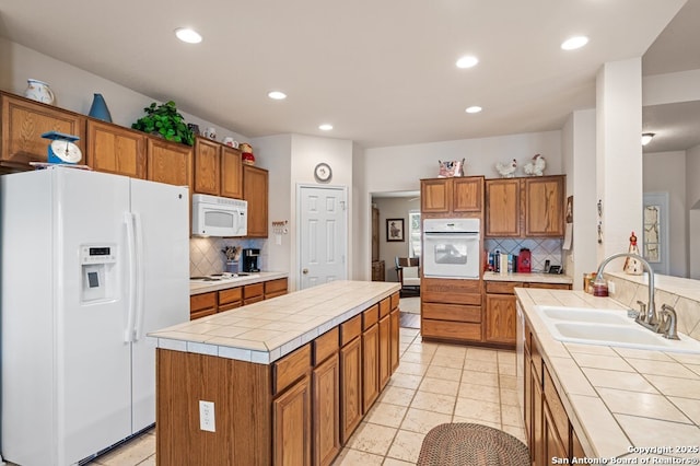 kitchen featuring sink, decorative backsplash, a center island, tile counters, and white appliances