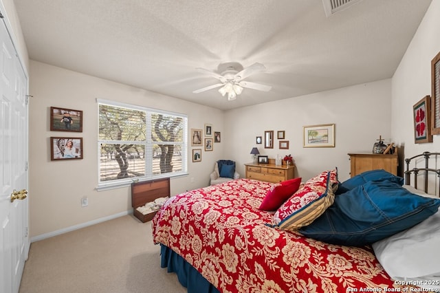 bedroom featuring ceiling fan, light colored carpet, and a textured ceiling