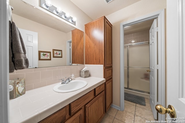 bathroom featuring vanity, decorative backsplash, and a shower with shower door