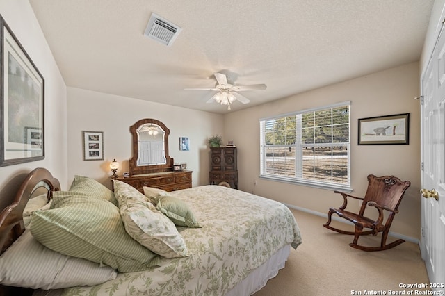 bedroom with light carpet, ceiling fan, and a textured ceiling