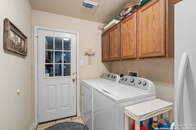 laundry room with cabinets, light tile patterned flooring, and washer and dryer