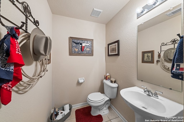 bathroom with tile patterned flooring, sink, a textured ceiling, and toilet