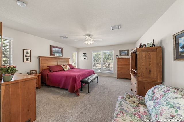 bedroom featuring ceiling fan, light colored carpet, and a textured ceiling