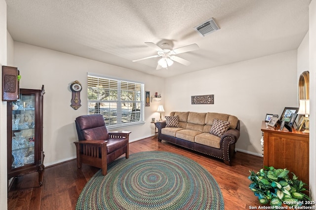 living room featuring ceiling fan, dark hardwood / wood-style flooring, and a textured ceiling