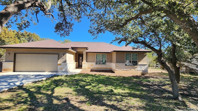 view of front of home with stucco siding, an attached garage, a front yard, stone siding, and driveway