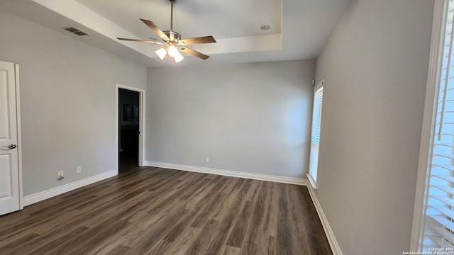 spare room with ceiling fan, dark hardwood / wood-style floors, and a raised ceiling