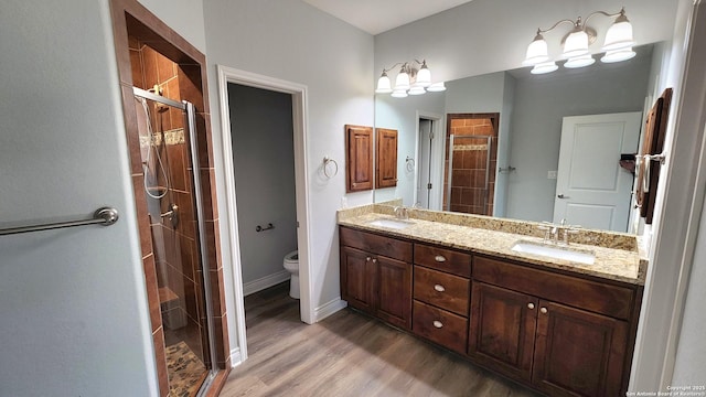 bathroom with a shower with door, vanity, hardwood / wood-style floors, and toilet