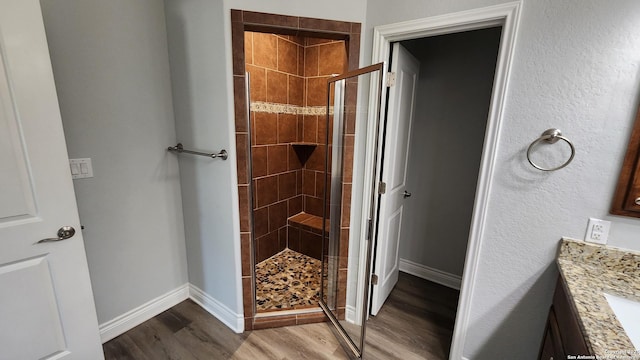 bathroom with wood-type flooring, vanity, and a shower with shower door