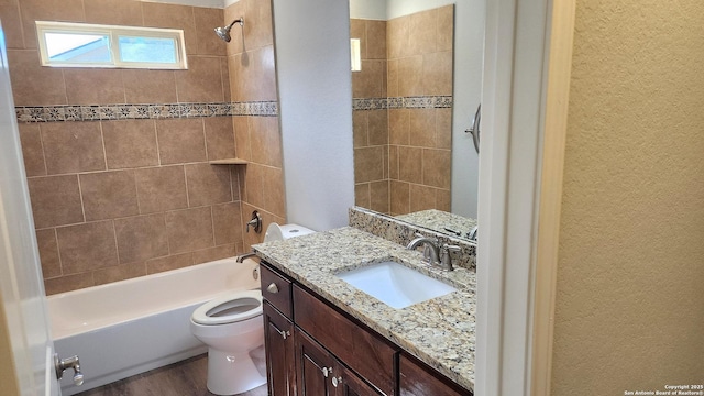 full bathroom with tiled shower / bath combo, vanity, hardwood / wood-style flooring, and toilet