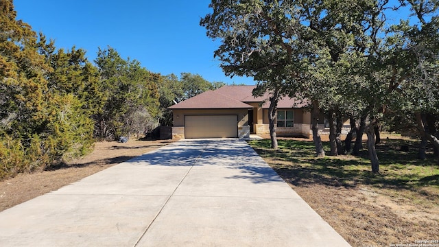 view of front of house with stone siding, an attached garage, concrete driveway, and stucco siding