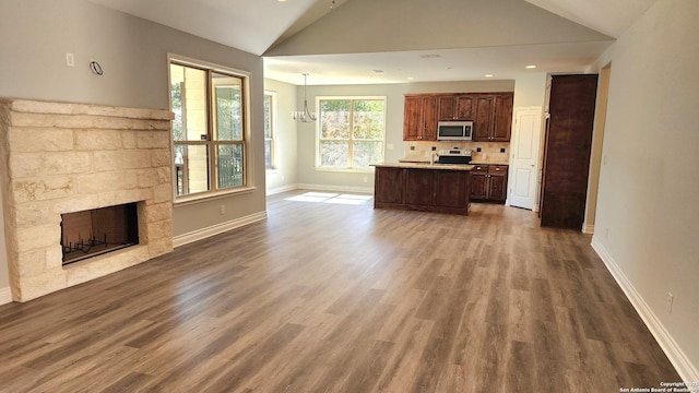 unfurnished living room with an inviting chandelier, lofted ceiling, a fireplace, and hardwood / wood-style floors