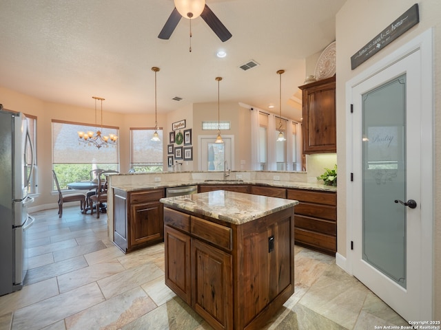 kitchen featuring a peninsula, visible vents, a sink, hanging light fixtures, and stainless steel appliances