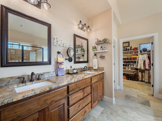 full bathroom with a shower stall, double vanity, a sink, and a walk in closet